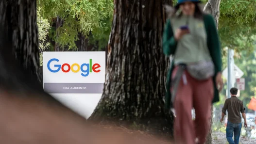 A Google office sign among trees with a pedestrian walking past