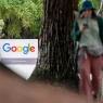 A Google office sign among trees with a pedestrian walking past