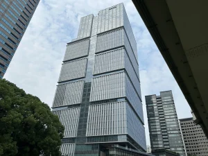 Low angle view of the Tokyo Garden Terrace Kioicho tower against a cloudy sky