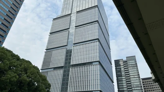 Low angle view of the Tokyo Garden Terrace Kioicho tower against a cloudy sky