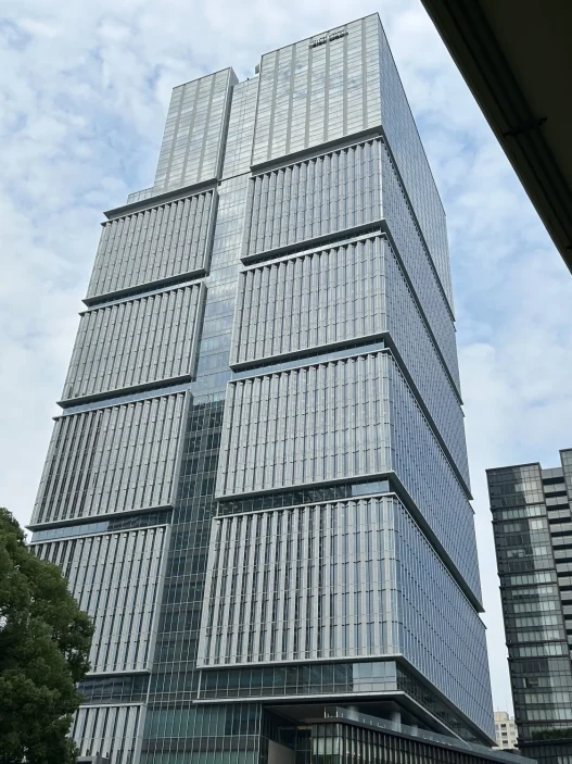 Low angle view of the Tokyo Garden Terrace Kioicho tower against a cloudy sky
